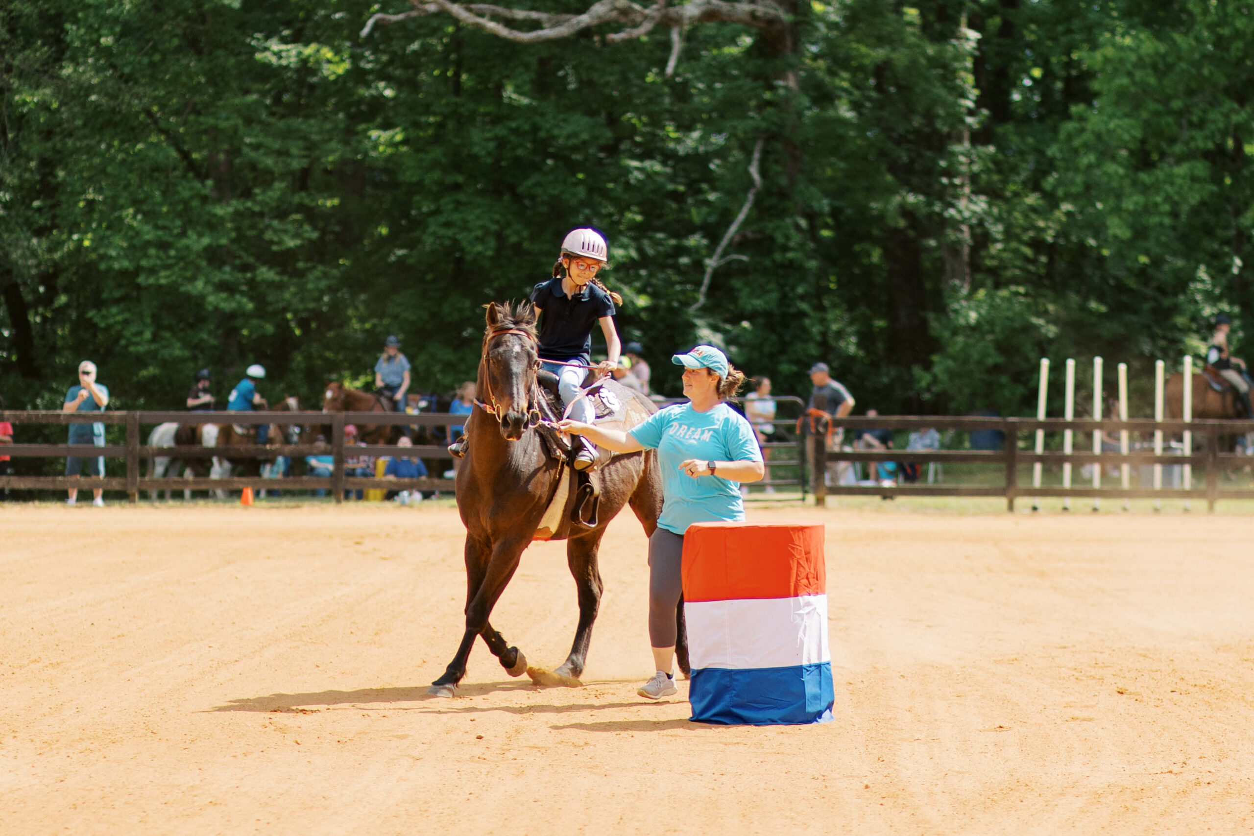 Student riding horse around barrels